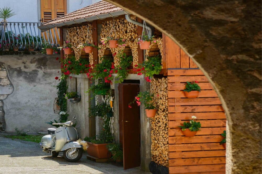 Casa tipica carnica a Illegio, con facciata in pietra e porticato in legno, esempio dell'architettura rurale e della cultura storica della regione.