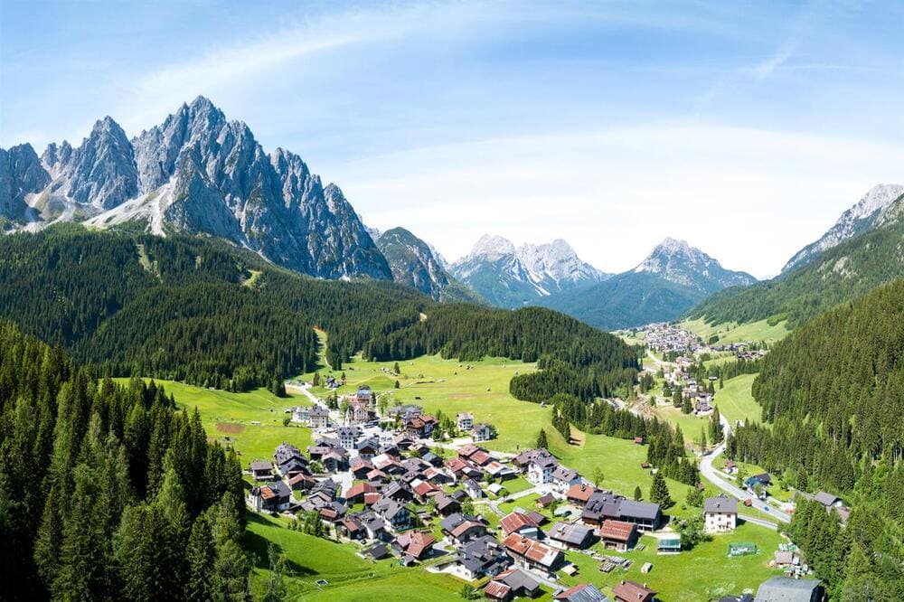 Foto aerea di Sappada in inverno, veduta dall'alto del paese innevato, caratteristiche montagne del Friuli-Venezia Giulia