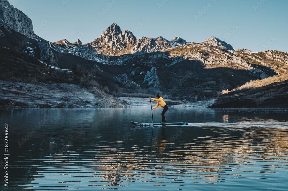 Praticante di SUP sul Lago del Predil in Friuli Venezia Giulia con le Alpi sullo sfondo